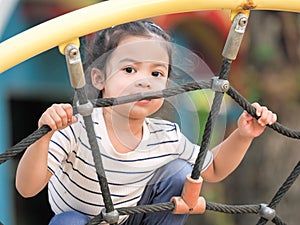 Young Asian girls are having fun clambering on rope nets in a playground