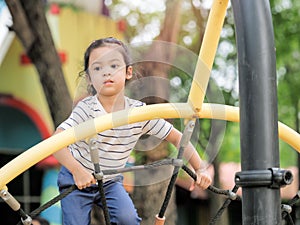 Young Asian girls are having fun clambering on rope nets in a playground