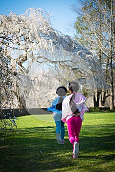 Young asian girls running in park with cherry blossoms