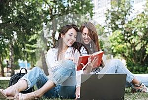 Young asian girls students working on laptop in city park