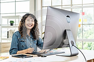Young Asian graphic designer woman working in an office with a computer