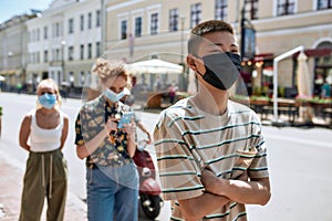 Young asian guy wearing mask waiting in line, respecting social distancing to enter takeout restaurant or to collect