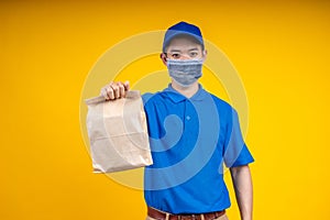 Young Asian handsome delivery man wearing mark holding a food paper bag