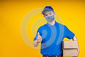 Young Asian handsome delivery man wearing mask holding box left arm