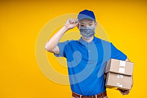 Young Asian handsome delivery man wearing mask holding boxs on left arm