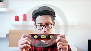 Young asian handyman holding leveler. Playing with air bubbles