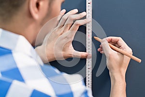 Young handyman sizing with yardstick and pencil photo
