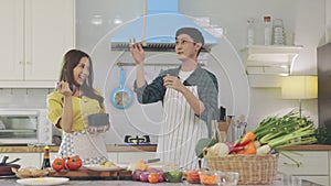 Young asian happy active family couple dancing laughing together preparing food at home,