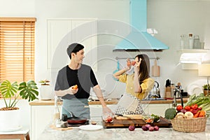 Young asian happy active family couple dancing laughing together preparing food at home, carefree joyful husband and wife having