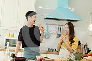 Young asian happy active family couple dancing laughing together preparing food at home, carefree joyful husband and wife having