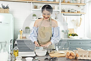 Young Asian housewife in kitchen cooking the bakery dough homemade