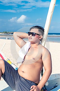 Young asian indonesian man relaxing on the beach of tropical Bali island, Indonesia.
