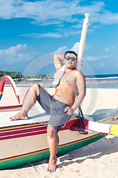 Young asian indonesian man relaxing on the beach of tropical Bali island, Indonesia.