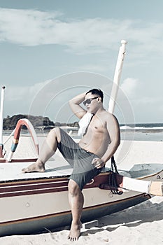 Young asian indonesian man relaxing on the beach of tropical Bali island, Indonesia.