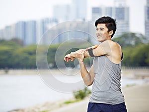 Young asian jogger stretching arms before running