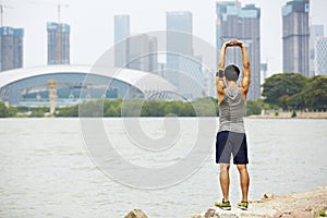 Young asian jogger stretching arms before running