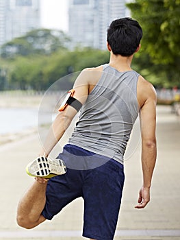 Young asian jogger stretching leg before running