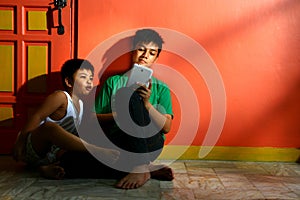 Young asian kids, brothers or siblings, with a tablet in a living room