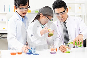 Young Asian kids wearing white scientist gown and do chemical test tube while study, learning in science classroom with teacher.