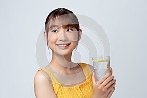 Young Asian lady enjoying healthy drink for beautiful skin and immunity on white