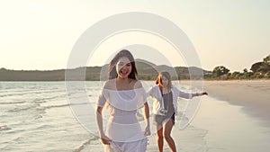 Young Asian lesbian couple running on beach. Beautiful women friends happy relax having fun on beach near sea when sunset in