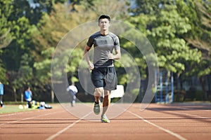 Young asian male athlete running on track
