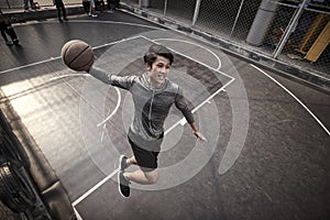 Young asian male basketball player attempting a dunk