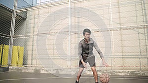 Young asian male basketball player training on outdoor court