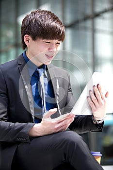 Young Asian male business executive using tablet PC