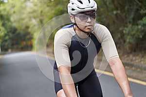 young asian male cyclist riding bicycle outdoors