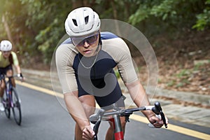 young asian male cyclist riding bicycle outdoors