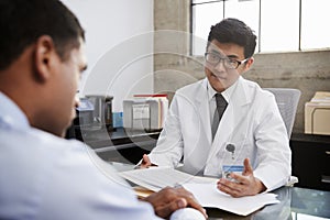 Young Asian male doctor in consultation with male patient photo