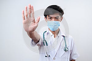 Young Asian male doctor wears madical face mask showing stop gesture