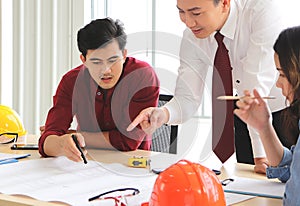 Young Asian male engineer working with his team discussing about the project at office table