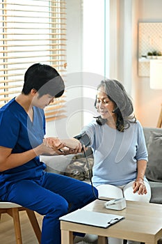 Young asian male medical worker measuring blood pressure of senior patient. Healthcare concept