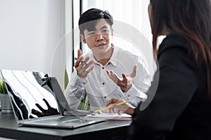 Young asian male mentor coach worker talking to female coworker teaching intern having business conversation with