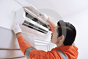 Giovane asiatico maschio tecnico riparazione l'aria condizionatore 