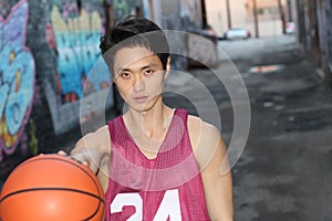 Young Asian male throwing basket ball with copy space outdoors