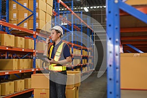 Young asian male worker wearing helmet using talki walki in modern warehouse