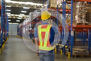 Young asian male worker wearing helmet using talki walki in modern warehouse