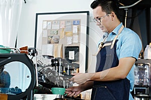 Young asian man barista making a cooffe cup at counter cafe back photo