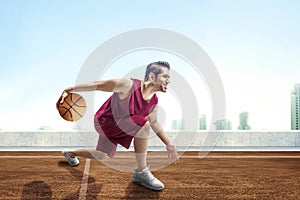 Young asian man basketball player posing in dribbling the ball between the legs on outdoor basketball court