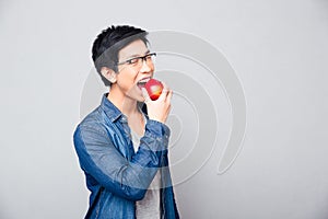 Young asian man bitting red apple