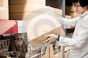 Young Asian man carrying cardboard boxes in warehouse