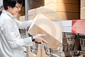 Young Asian man carrying cardboard boxes in warehouse