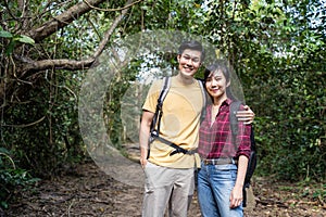 Young Asian man and Caucasian woman friend traveling in the forest together. They are feeling fresh and relax in nature wild, look