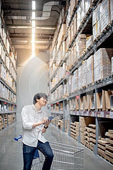 Young Asian man checking the shopping list in warehouse