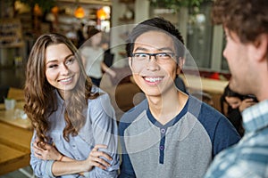 Young asian man and cheerful woman listening to their friend