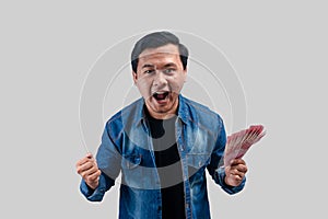 Young Asian man clenched fist while holding paper money