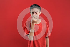 Young Asian man close his nose for bad smell, on red color